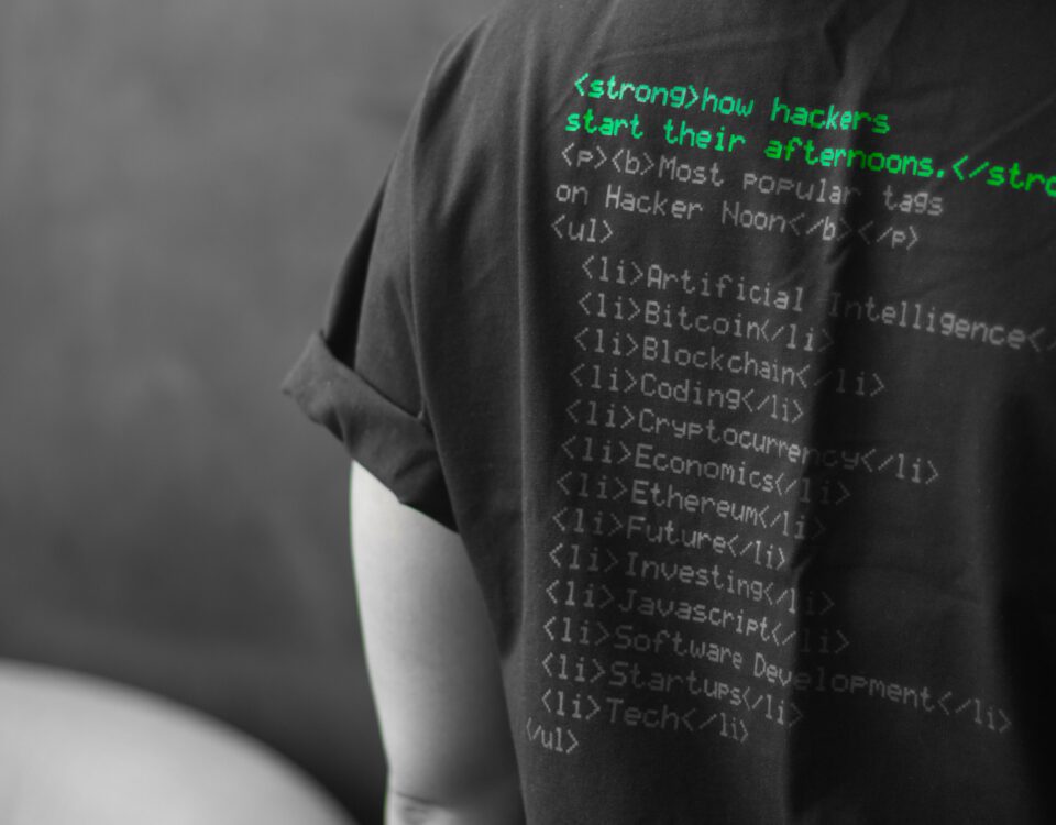 Haker w koszulce z nadrukowanym kodem źródłowym na plecach.