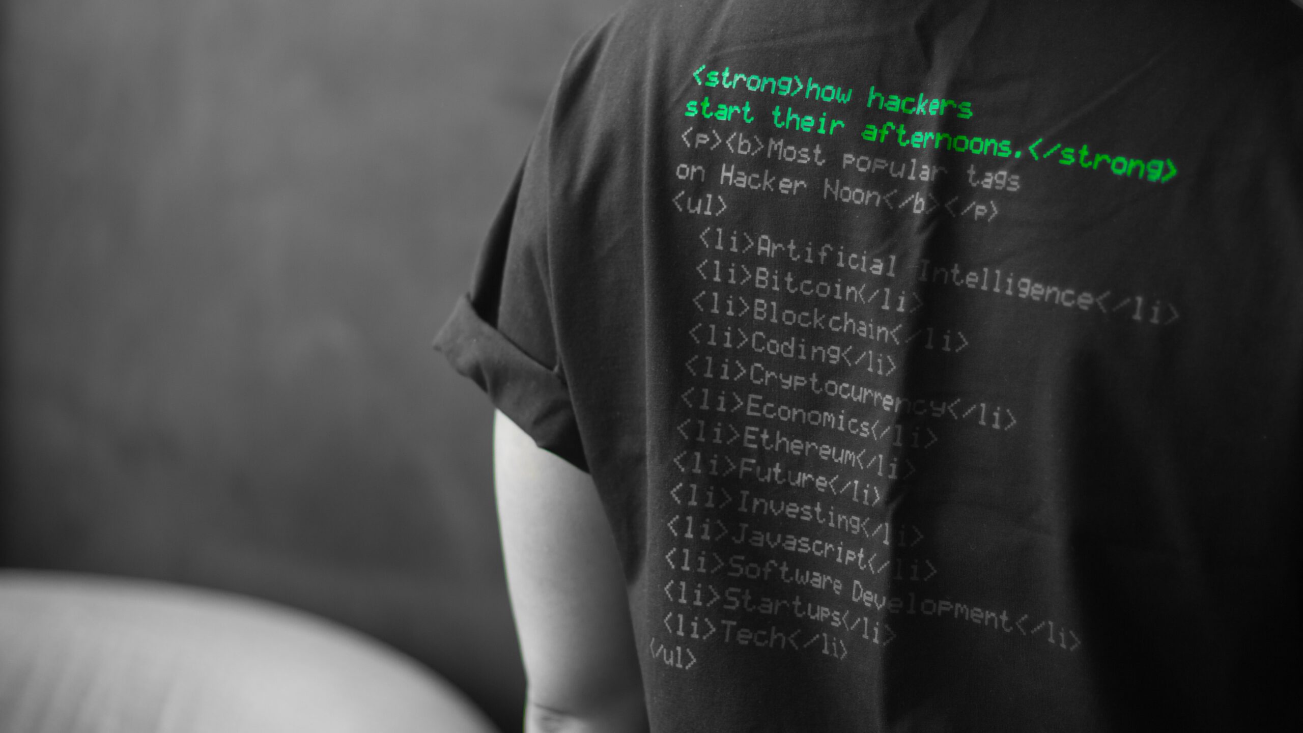 Haker w koszulce z nadrukowanym kodem źródłowym na plecach.
